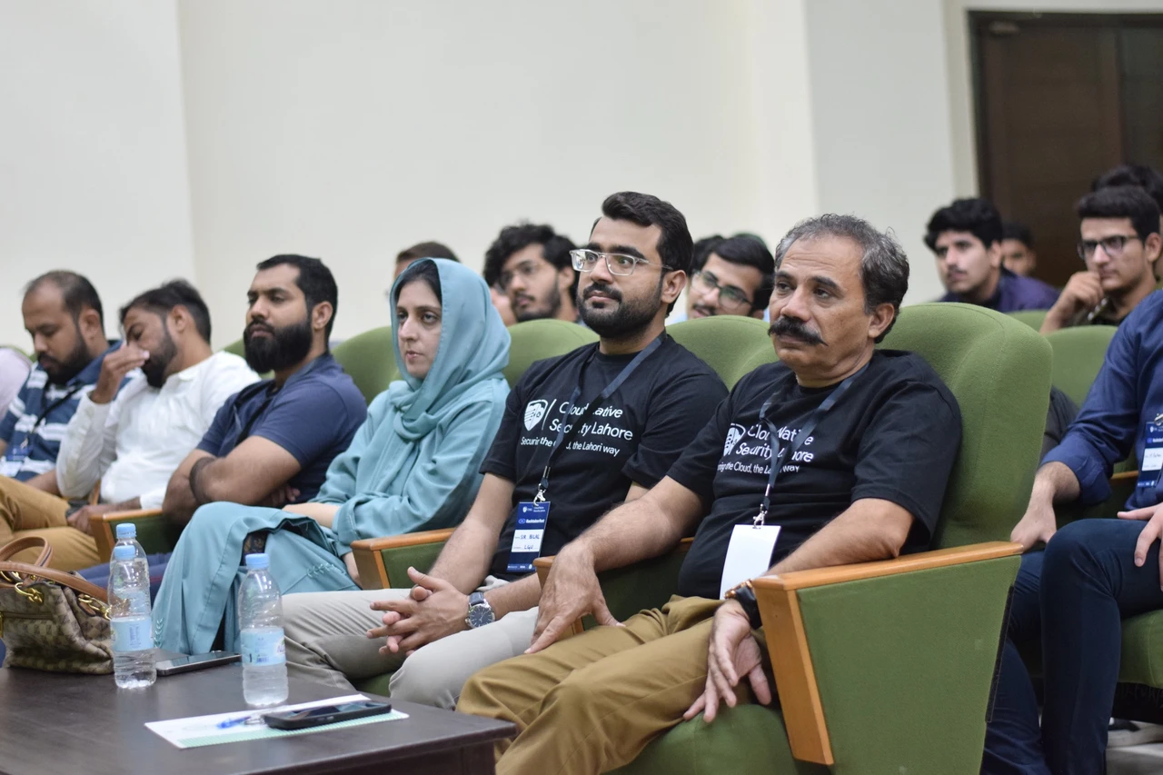 Front-row guests in Cloud Native Security Lahore shirts listen to the talk.