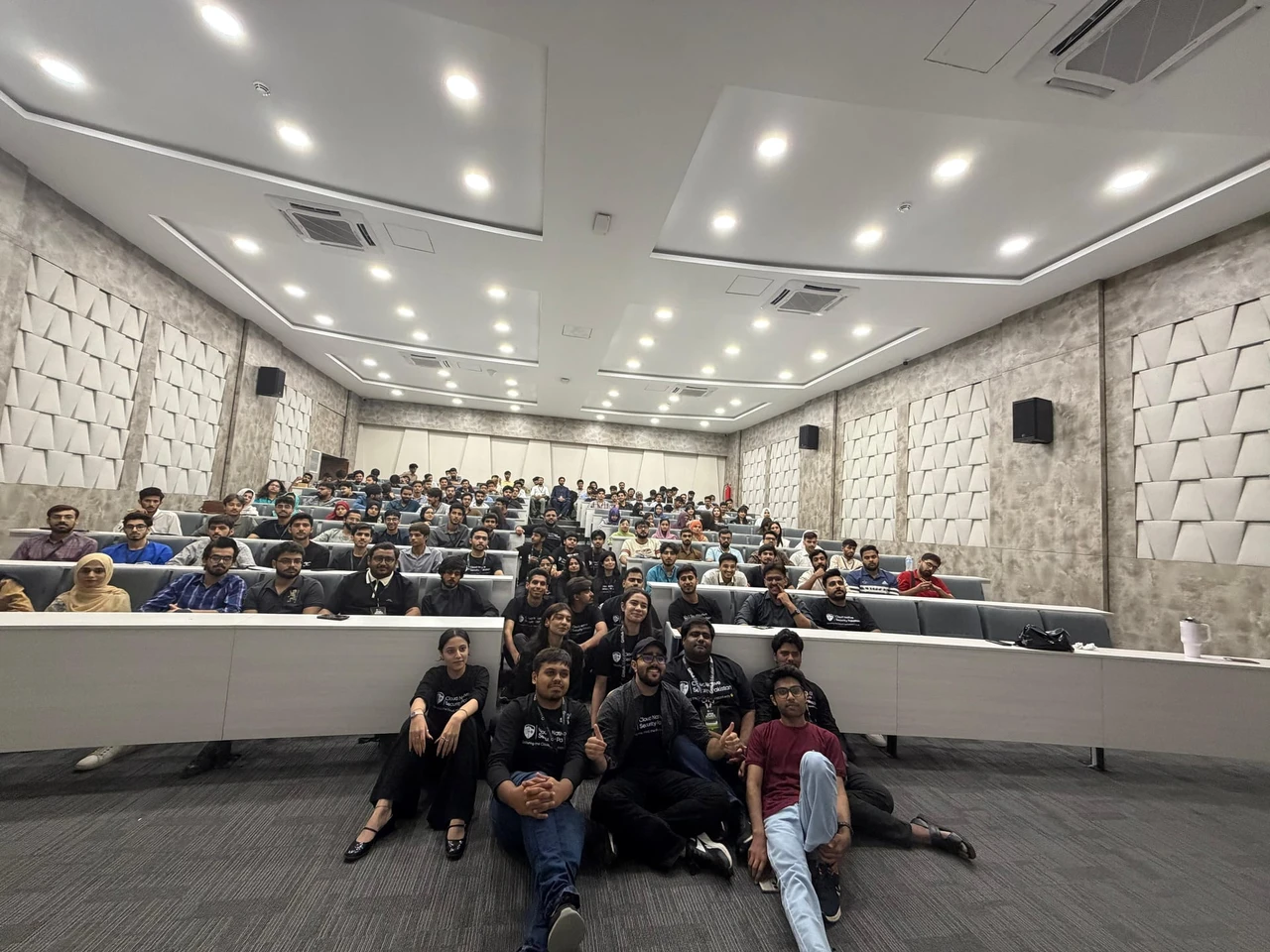 Attendees seated across the tiered lecture hall with organizers gathered at the front